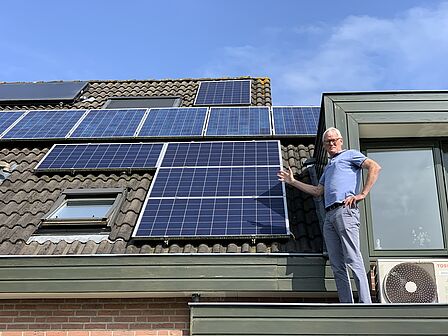 energieambassadeur Ad van Rooijen naast de zonnepanelen op zijn dak 
