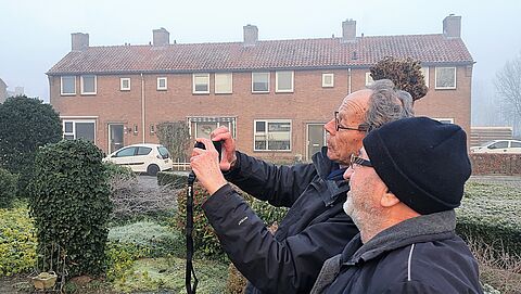 een energieambassadeur en een inwoner kijken samen naar het scherm van een warmtebeeldcamera